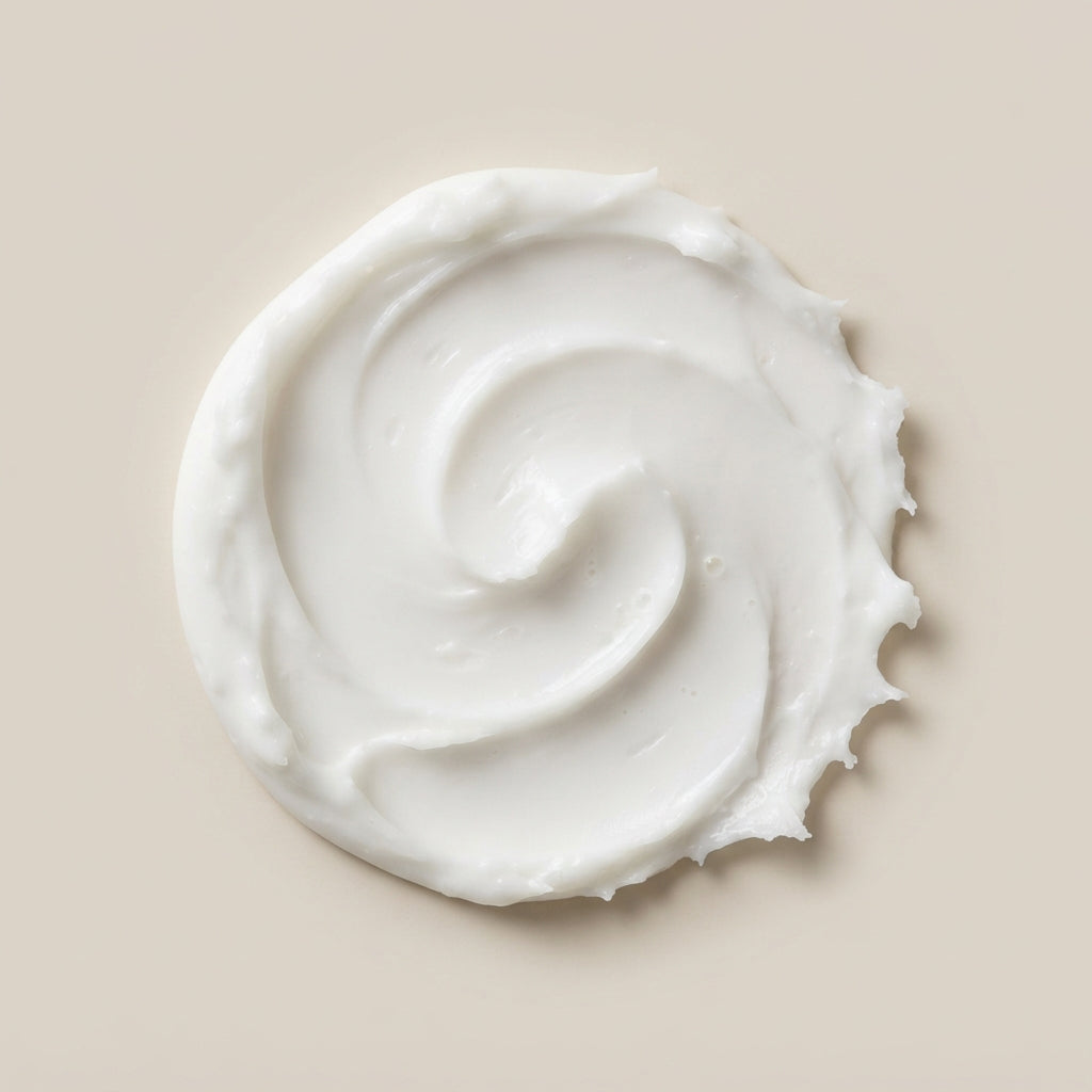 A swirl of thick, creamy white lotion or body butter on a solid beige background.