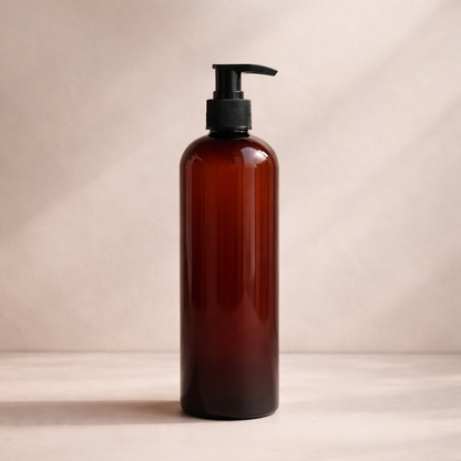 Minimalist amber shampoo bottle with black pump on a warm neutral background, softly lit with subtle shadow for depth.