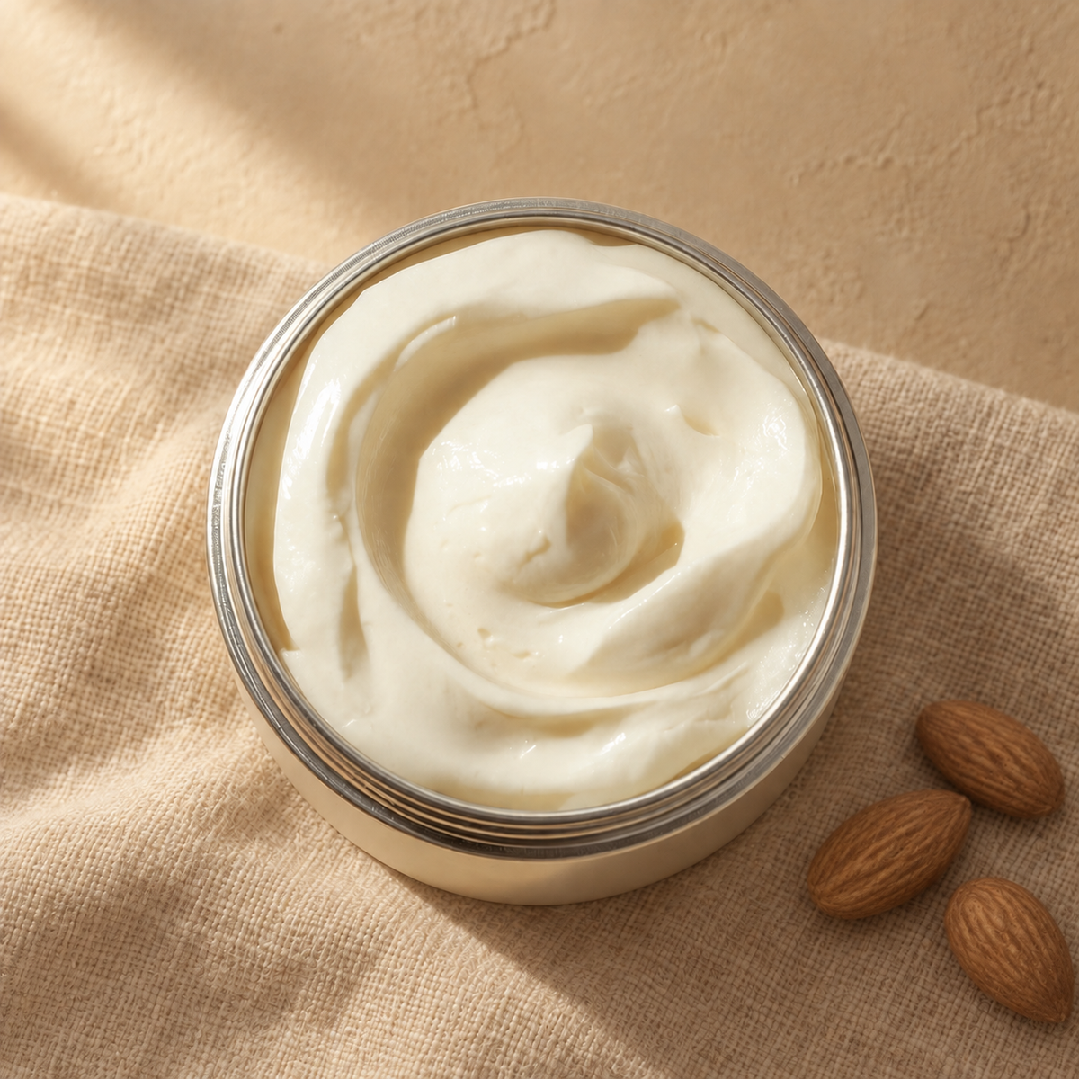 Almond whipped body butter in a silver tin on unbleached linen with whole almonds beside it — PureButterMelts